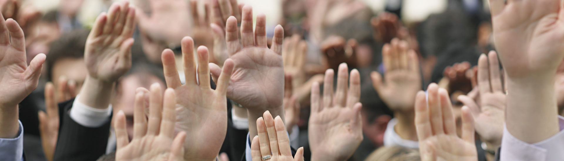 Closeup of business crowd raising hands