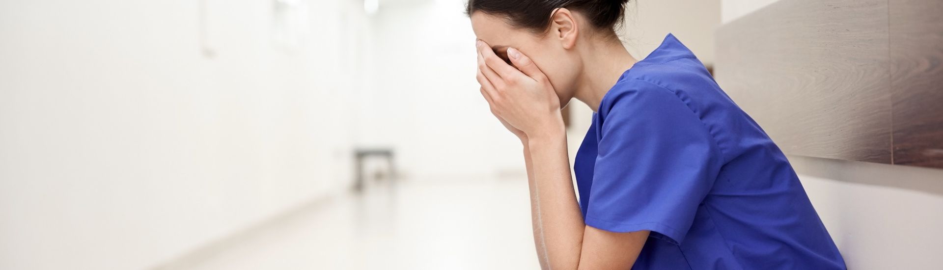 sad or crying female nurse at hospital corridor