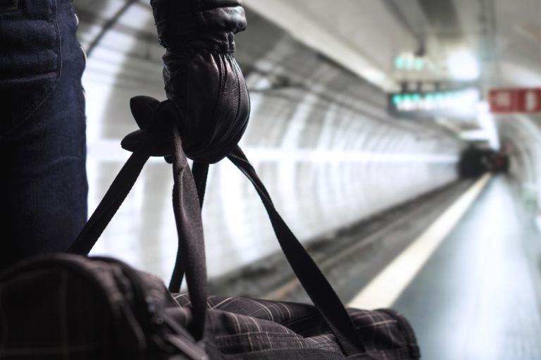 Terrorist in subway tunnel. Man planning bomb attack and strike in underground. Criminal standing in metro tunnel. Black bag and leather gloves. Security threat in public transportation concept.