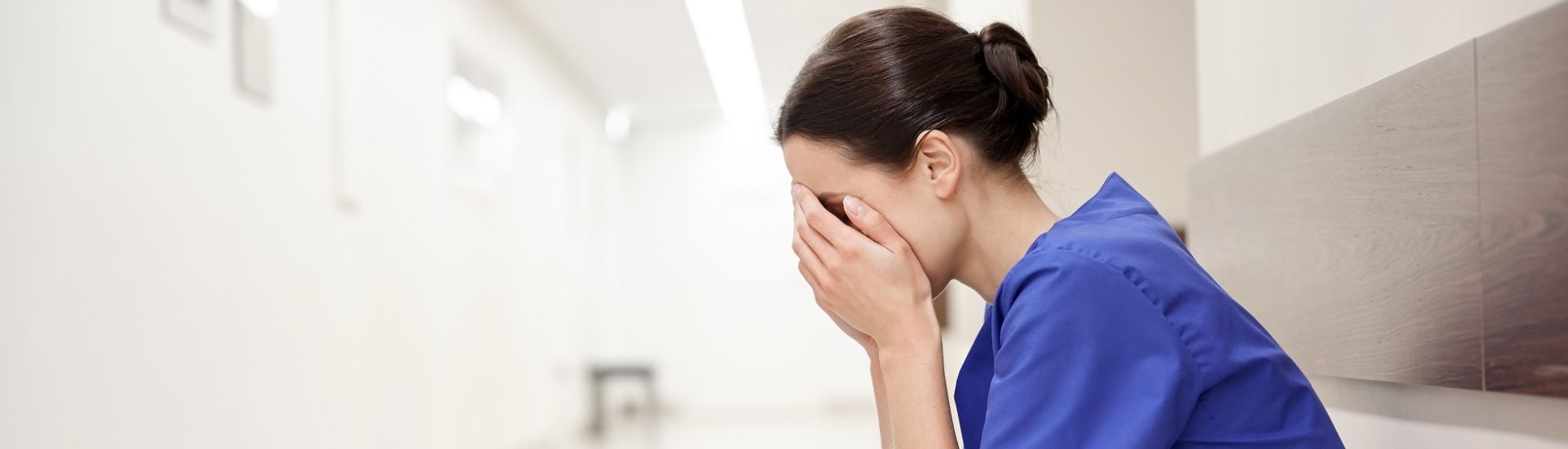 sad or crying female nurse at hospital corridor