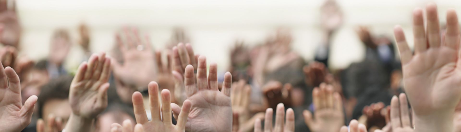 Closeup of business crowd raising hands