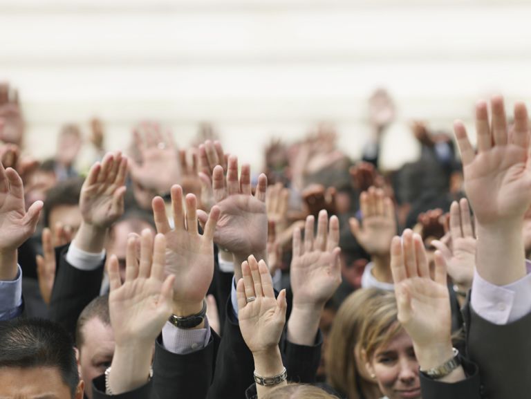 Closeup of business crowd raising hands