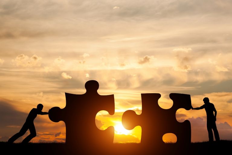 Two men connect two puzzle pieces. Concept of business solution, solving a problem.