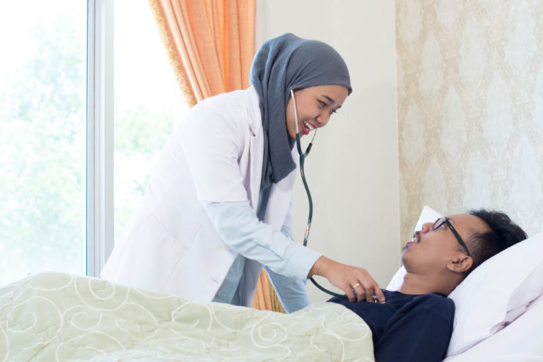 Muslim Female doctor and her male patient inside hospital clinic room doing examination with stethoscope