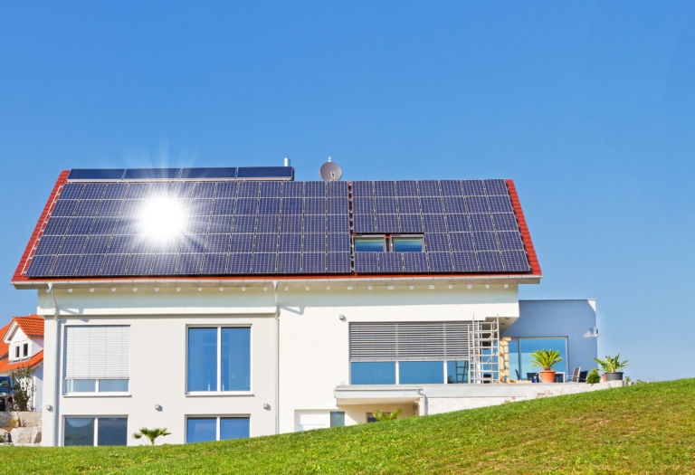 Haus mit Solarzellen und Sonne