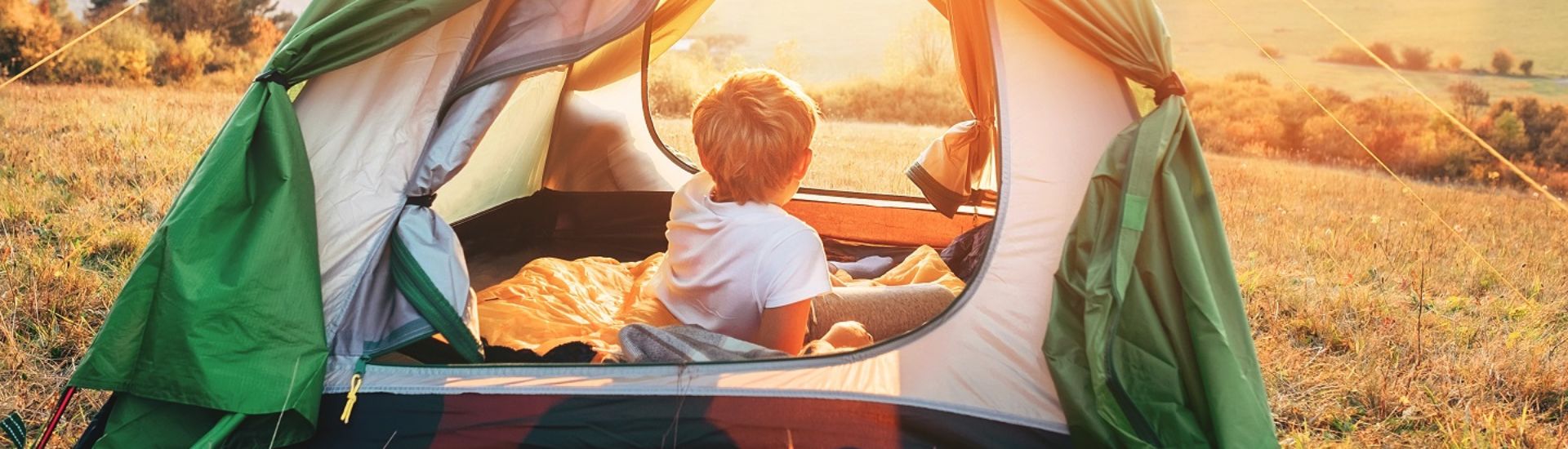 Boy rest in camping tent and enjoy with sunset light in mountain valley