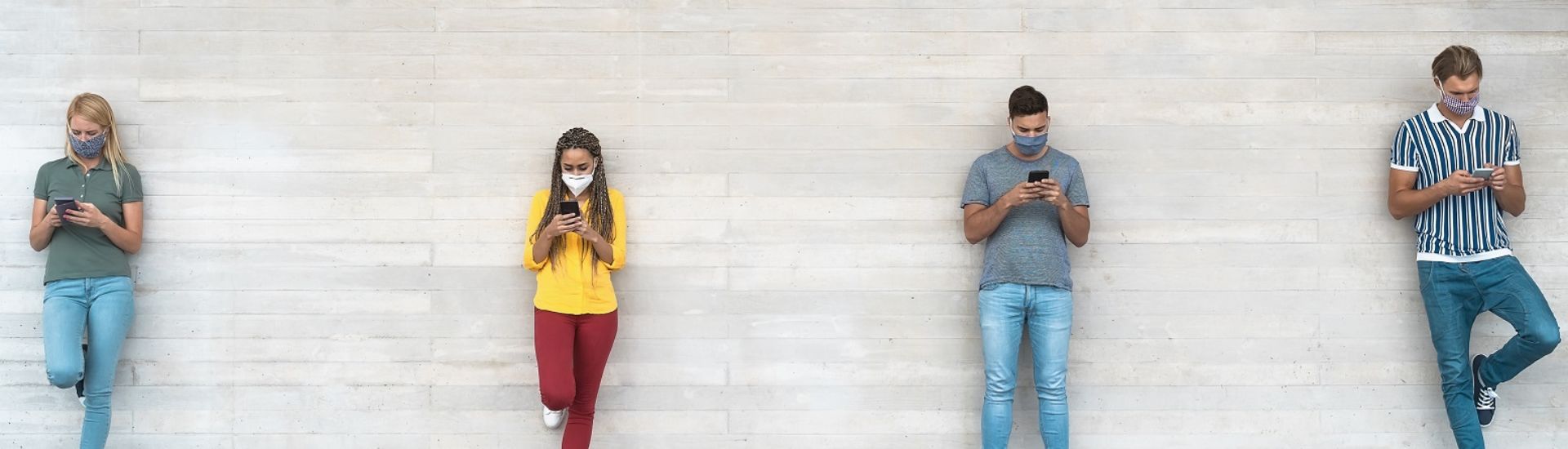 Young people wearing surgical mask using mobile phone keeping social distance – Millennial friends watching media trends on smartphones during corona virus outbreak – Youth and technology concept