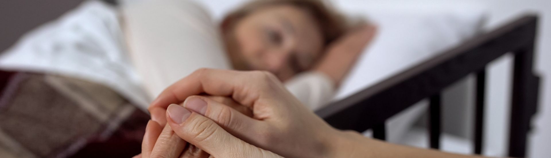 Daughter supporting her terminally ill mother lying on hospital bed, hospice