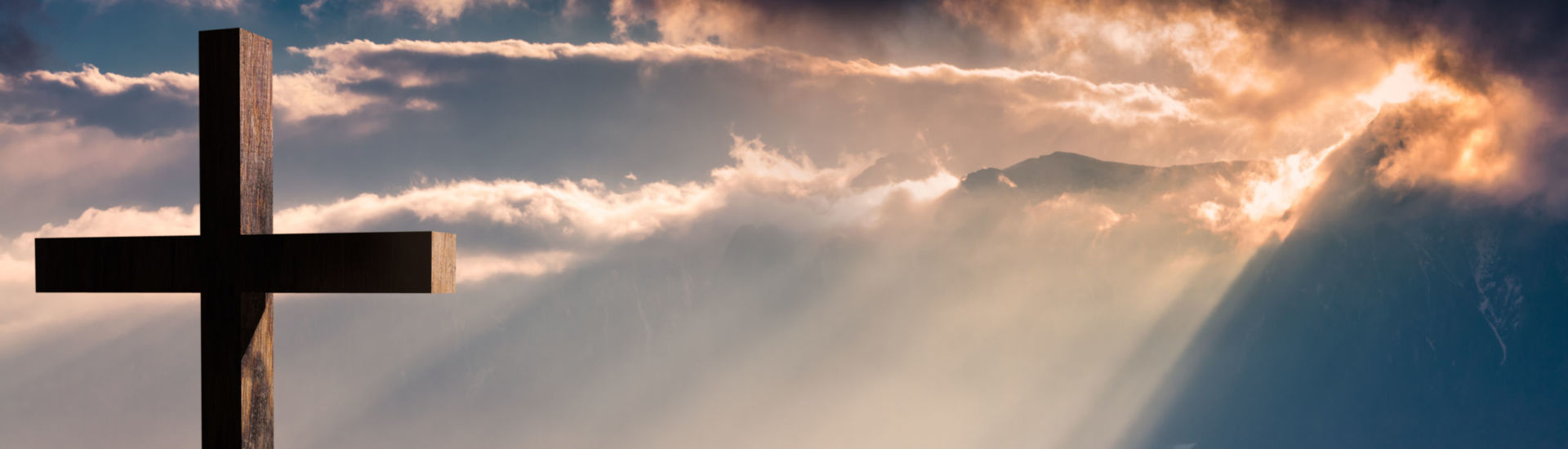 Jesus Christ cross. Easter, resurrection concept. Christian cross on a background with dramatic lighting, colorful mountain sunset, dark clouds and sky and sunbeams