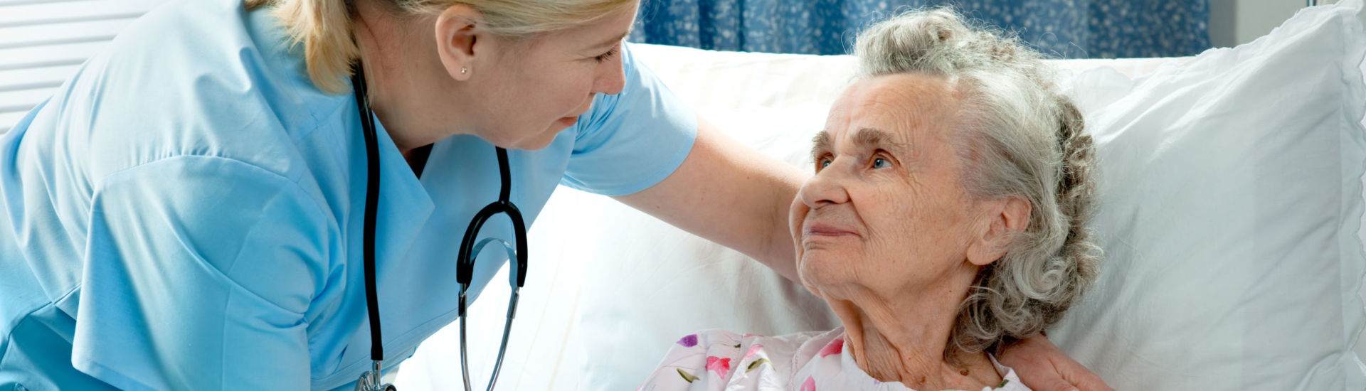 Nurse cares for a elderly woman lying in bed