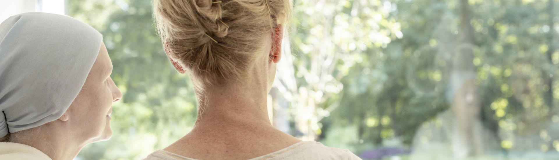Panorama of nurse and sick elderly woman with headscarf looking