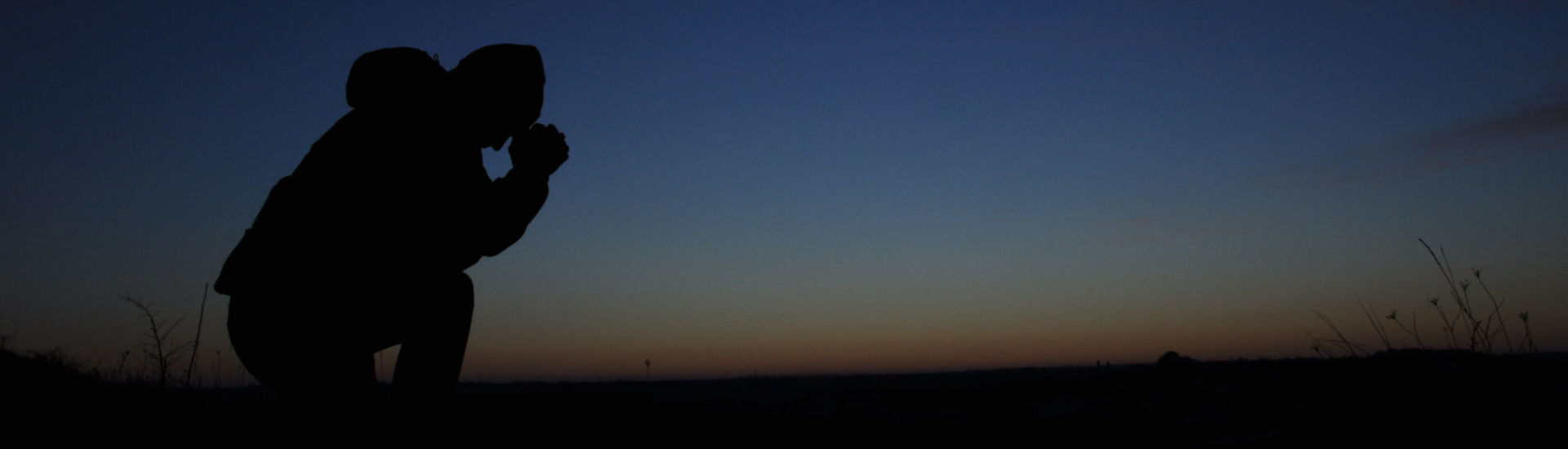 Prayer. Repentance. Silhouetted men on a background of blue sky