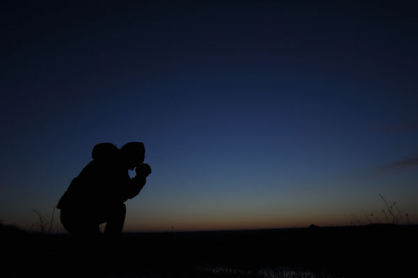 Prayer. Repentance. Silhouetted men on a background of blue sky