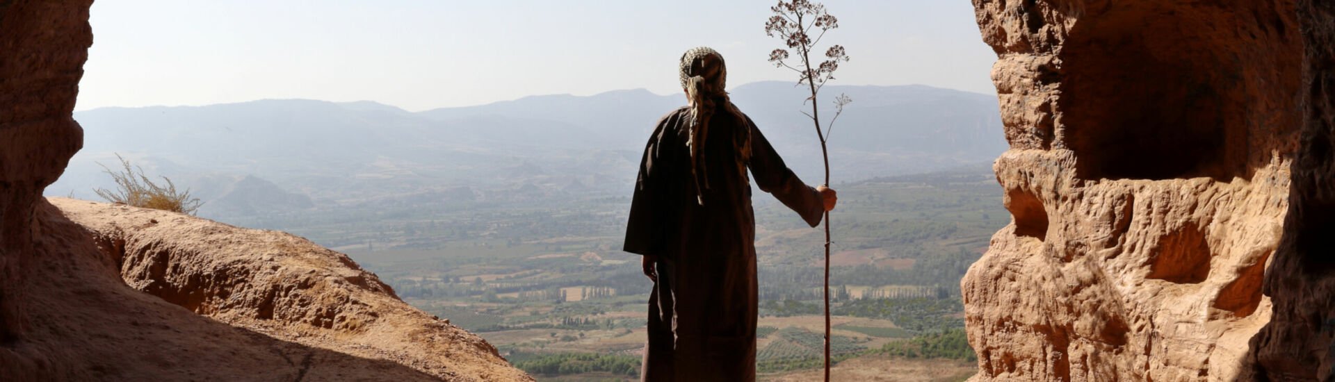 HERMIT  MAN LOOKING TO THE VALLEY FROM A HIGH CAVE WITH A BRANCH