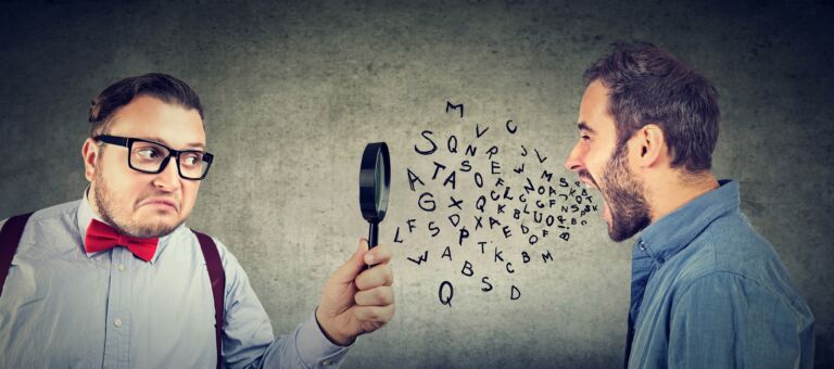 Curious businessman looking through a magnifying glass at an angry screaming man