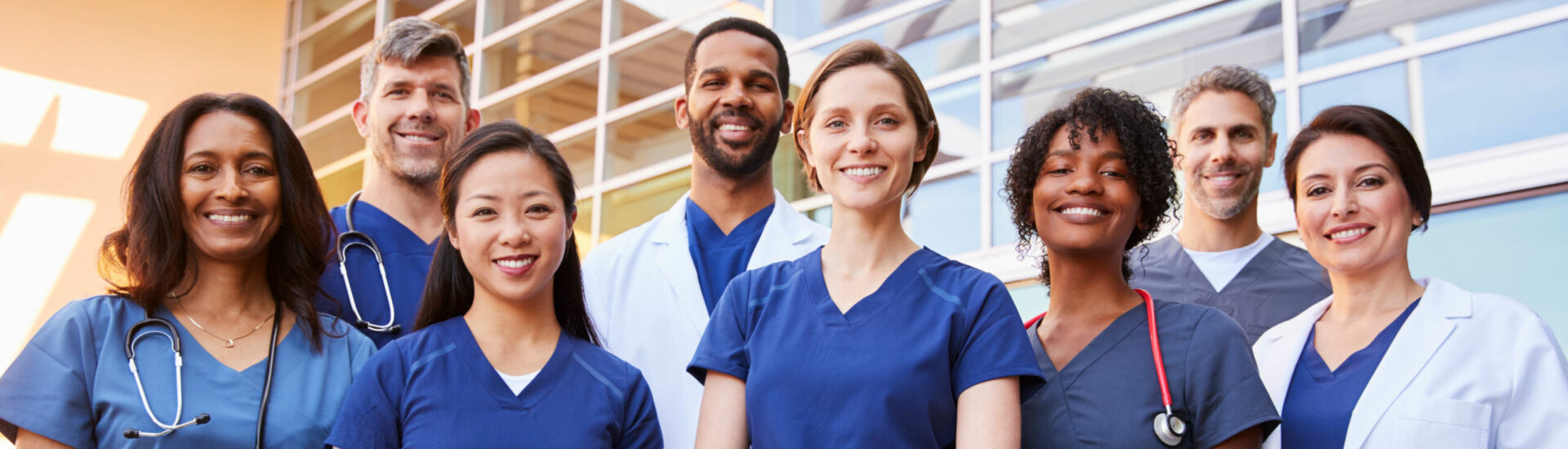 Smiling medical team standing together outside a hospital
