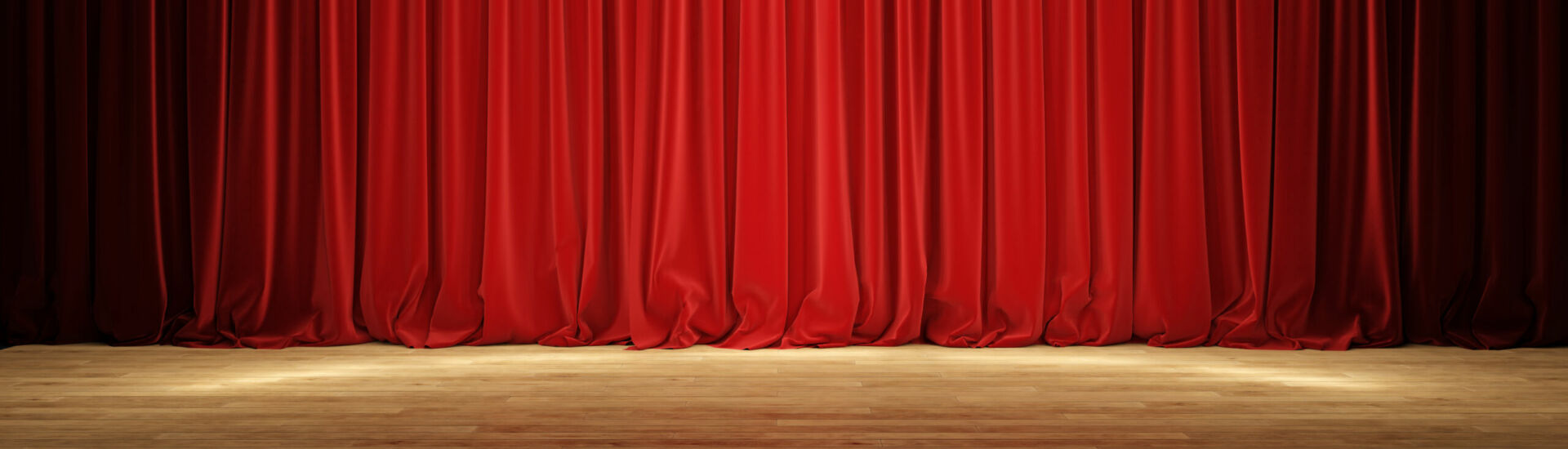 Empty theater stage with red velvet curtains.
