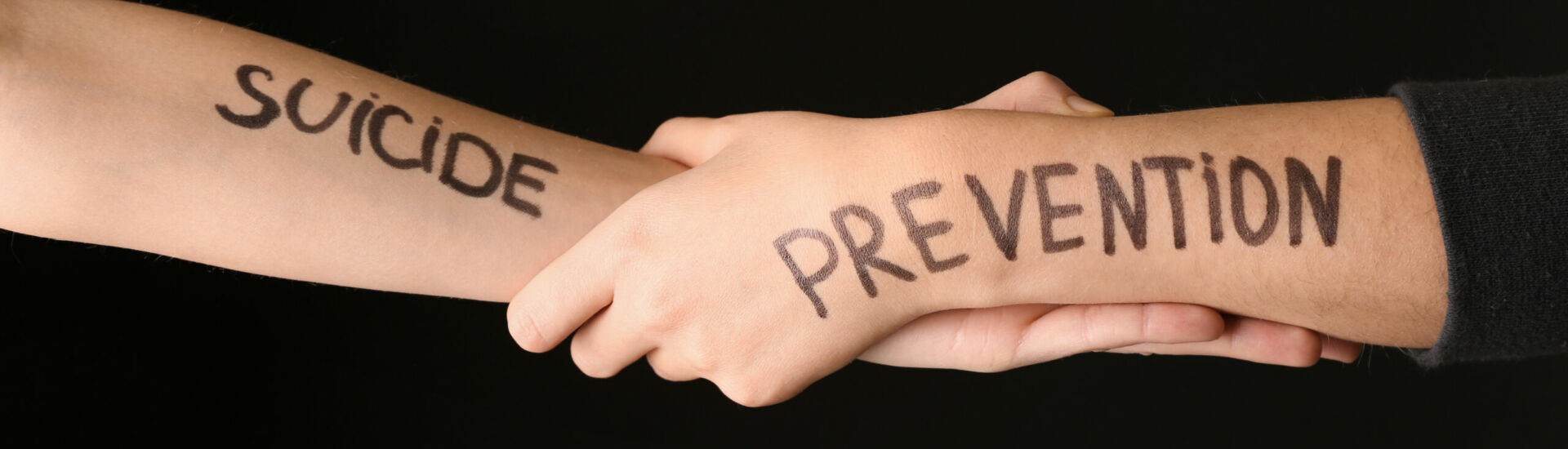 Female hands with text SUICIDE PREVENTION on dark background