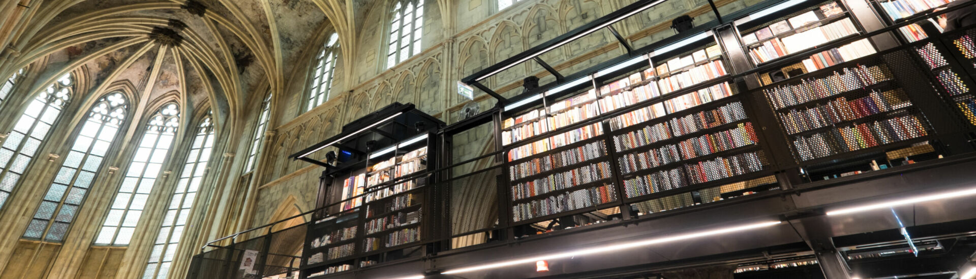 Interior of Dominican church converted into a bookstore with restaurant, customers, cathedral ceilings and pillars of the church in Maastricht, Netherlands