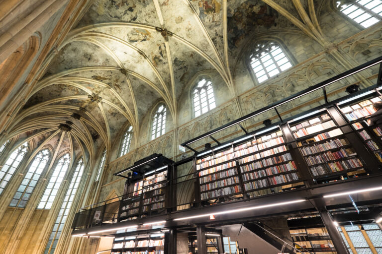 Interior of Dominican church converted into a bookstore with restaurant, customers, cathedral ceilings and pillars of the church in Maastricht, Netherlands