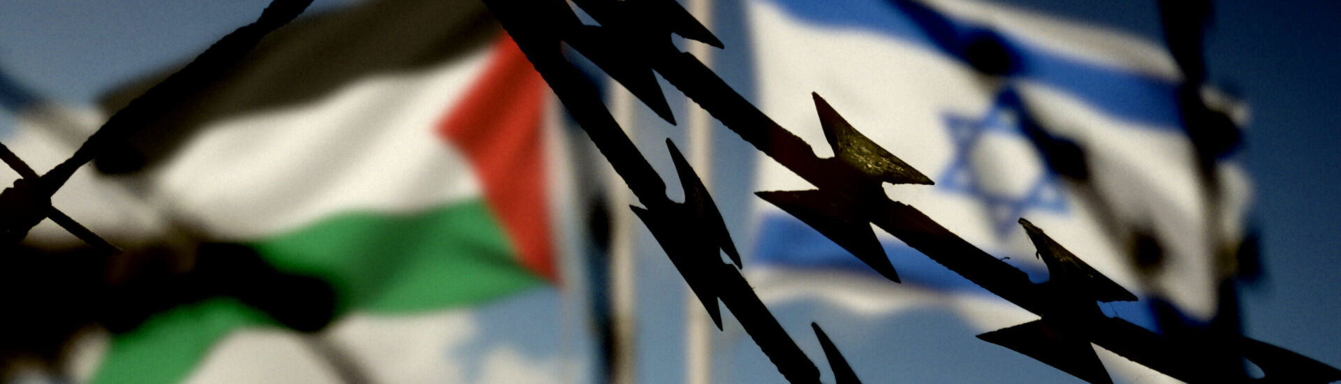 Flaggen von Israel und Palästina hinter dem Stacheldraht