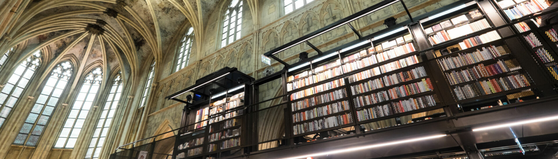 Interior of Dominican church converted into a bookstore with restaurant, customers, cathedral ceilings and pillars of the church in Maastricht, Netherlands