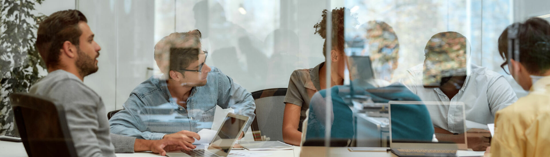 Setting Goals. Group of business people communicating and discussing fresh ideas while sitting together behind the glass wall in the meeting room