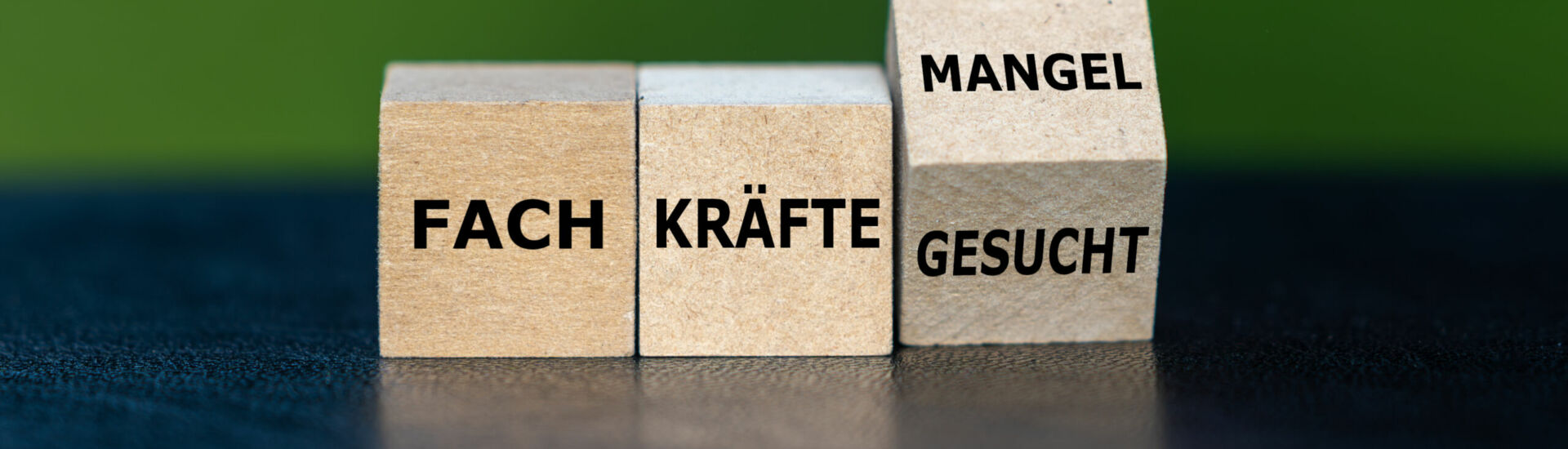 Hand dreht Würfel und ändert den Ausdruck ‚Fachkräfte gesucht‘ in ‚Fachkräftemangel‘.
