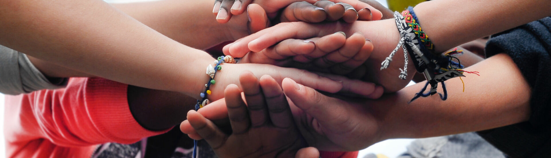 Multiracial teen friends joining hands together in cooperation