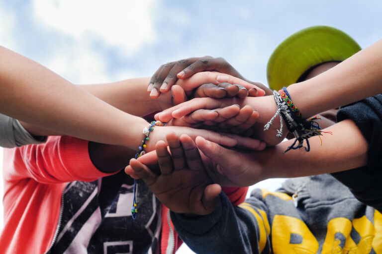 Multiracial teen friends joining hands together in cooperation