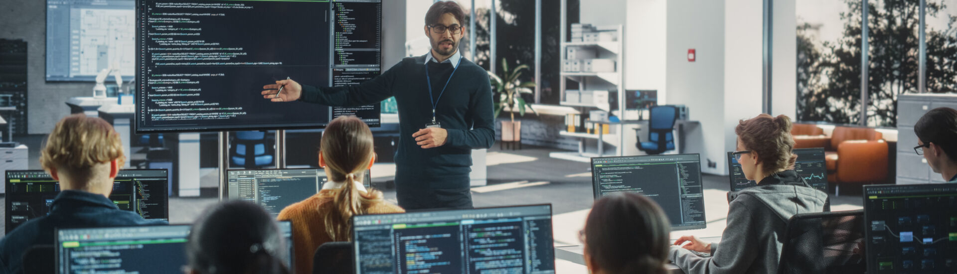 Knowledgeable Teacher Giving a Lecture About Software Engineering to a Group of Smart Diverse University Students. International Undergraduates Sitting Behind Desks with Computers