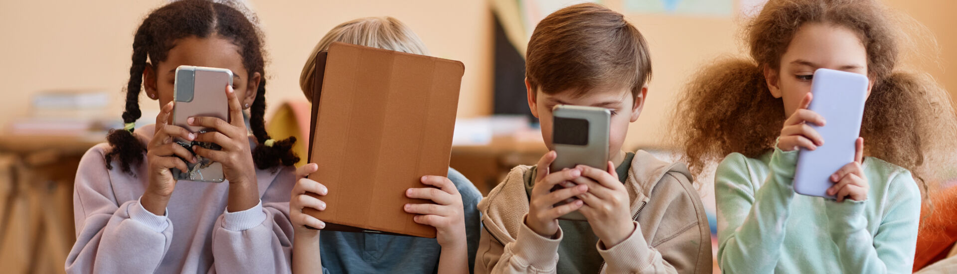 Group of young children holding smartphones and hiding faces